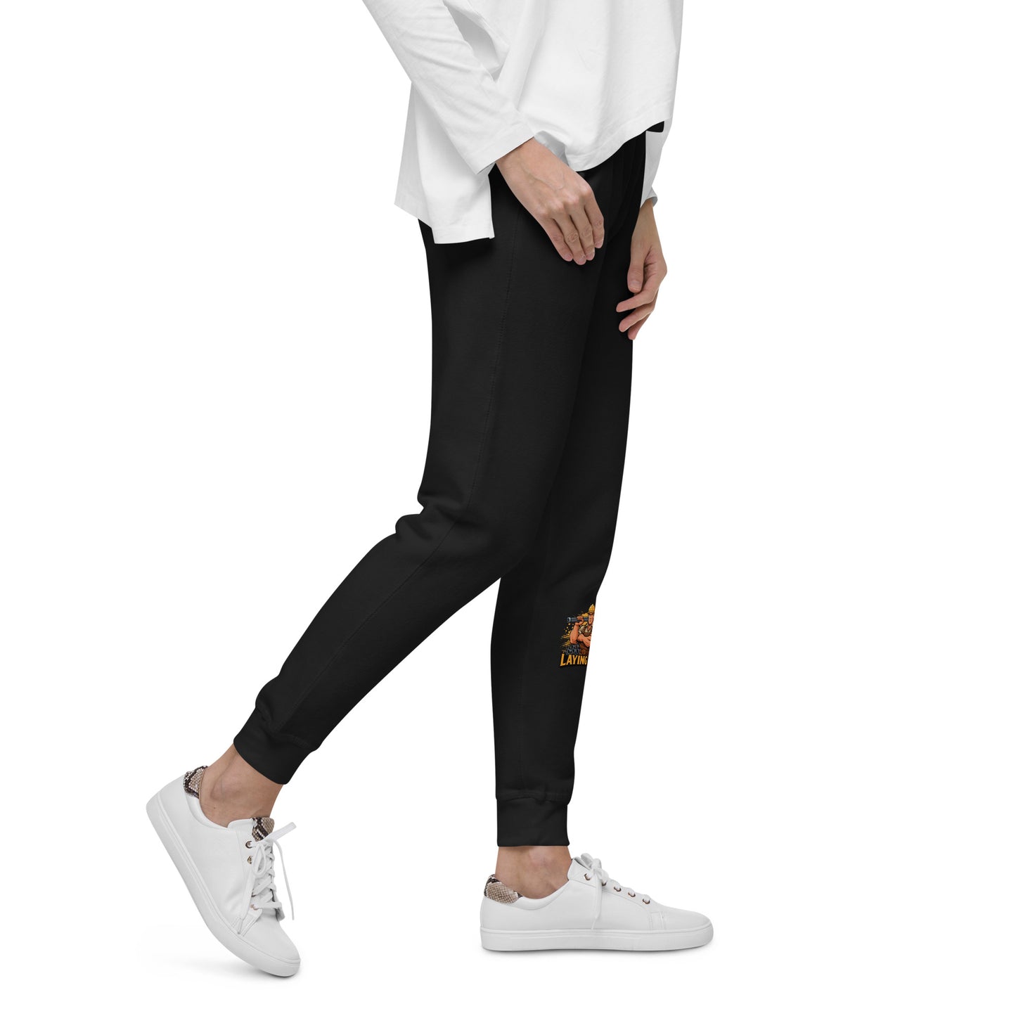 Person wearing black jogger pants with a logo and white sneakers on a white background